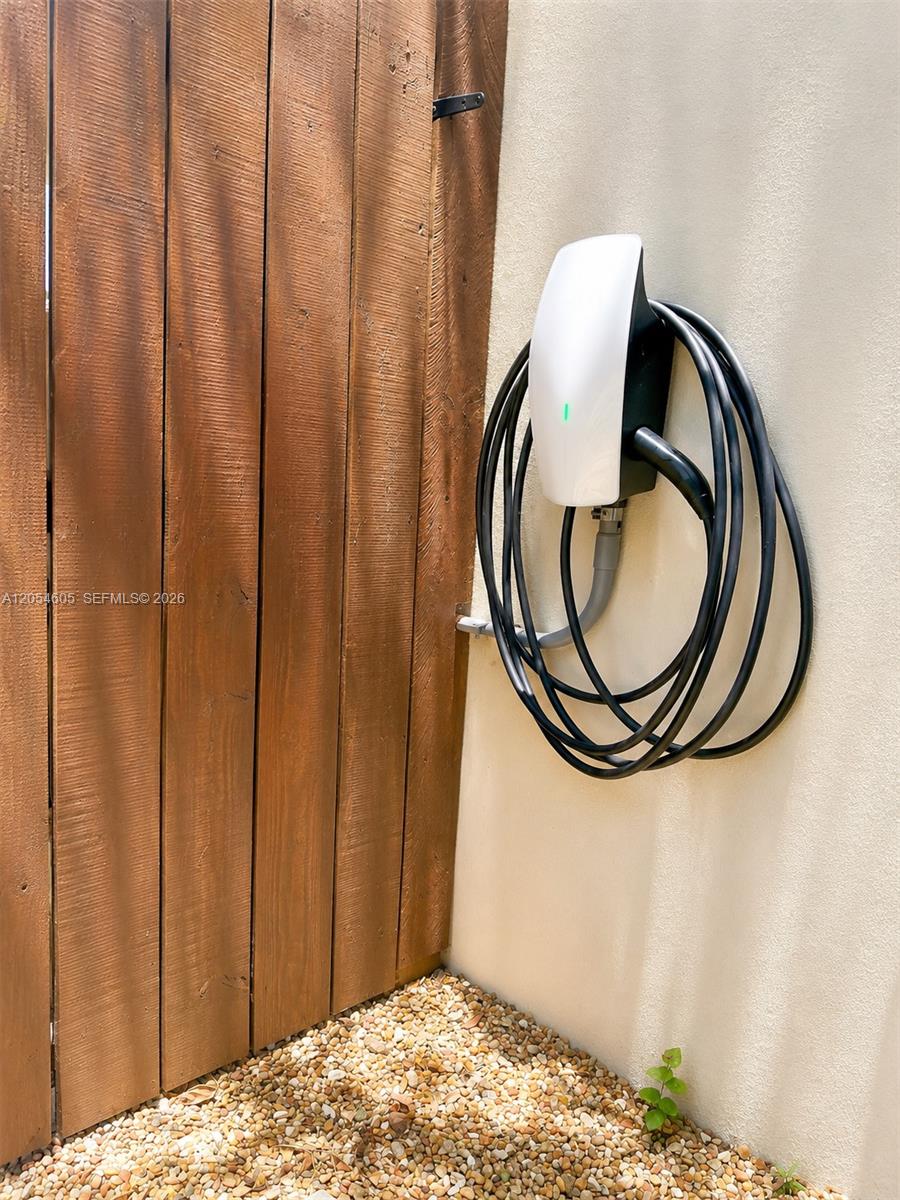 3538 Southwest 1st Avenue, Unit 1 Miami, FL 33145 - Photo 18 of 20 Convenient electric-vehicle charging station installed outdoors, featuring a wall-mounted charger with an organized charging cable. This practical amenity provides easy at-home charging beside the property’s private fenced area.