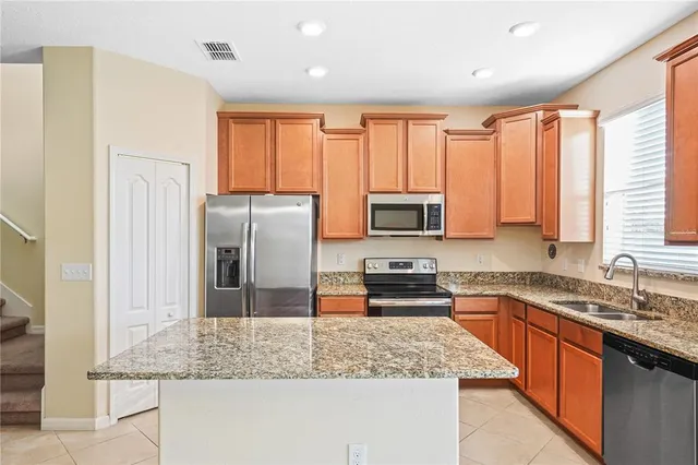 a kitchen with stainless steel appliances granite countertop a stove refrigerator sink and microwave