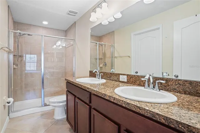 a bathroom with a granite countertop sink a toilet a mirror and shower