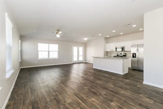 a view of kitchen with kitchen island wooden floors and stainless steel appliances