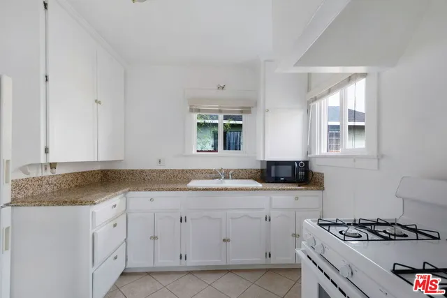 a kitchen with granite countertop a sink stove and cabinets