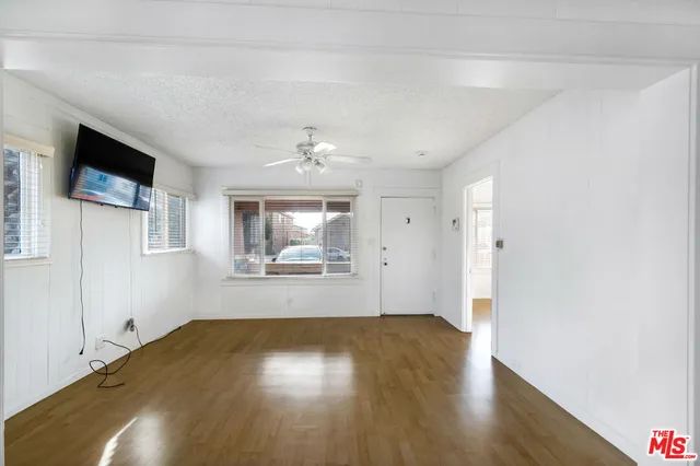 a view of empty room with wooden floor and fan