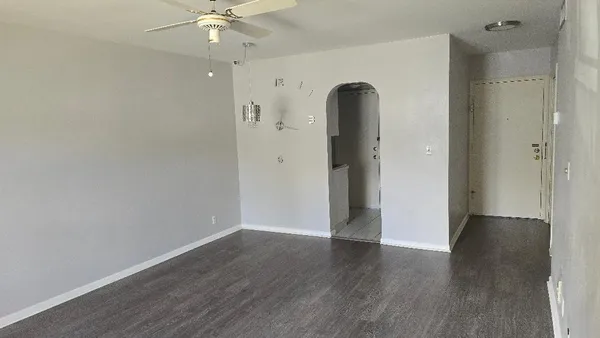 an empty room with wooden floor and a ceiling fan
