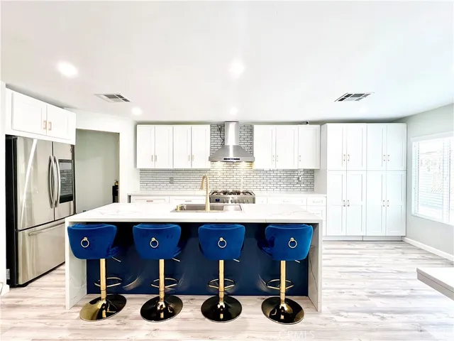 a kitchen with stainless steel appliances kitchen island granite countertop a table chairs in it and wooden floors