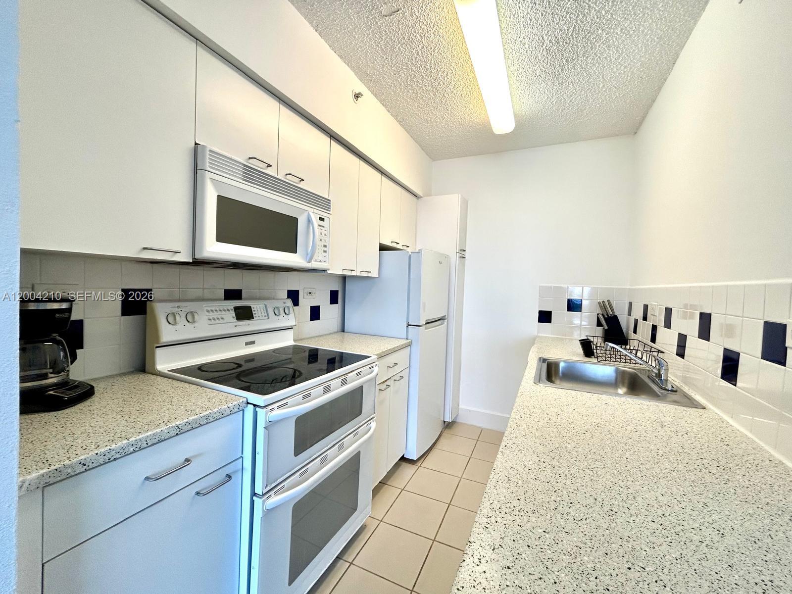 1500 Bay Road, Unit 1172S Miami Beach, FL 33139 - Photo 15 of 15 a kitchen with stainless steel appliances granite countertop a sink stove and cabinets