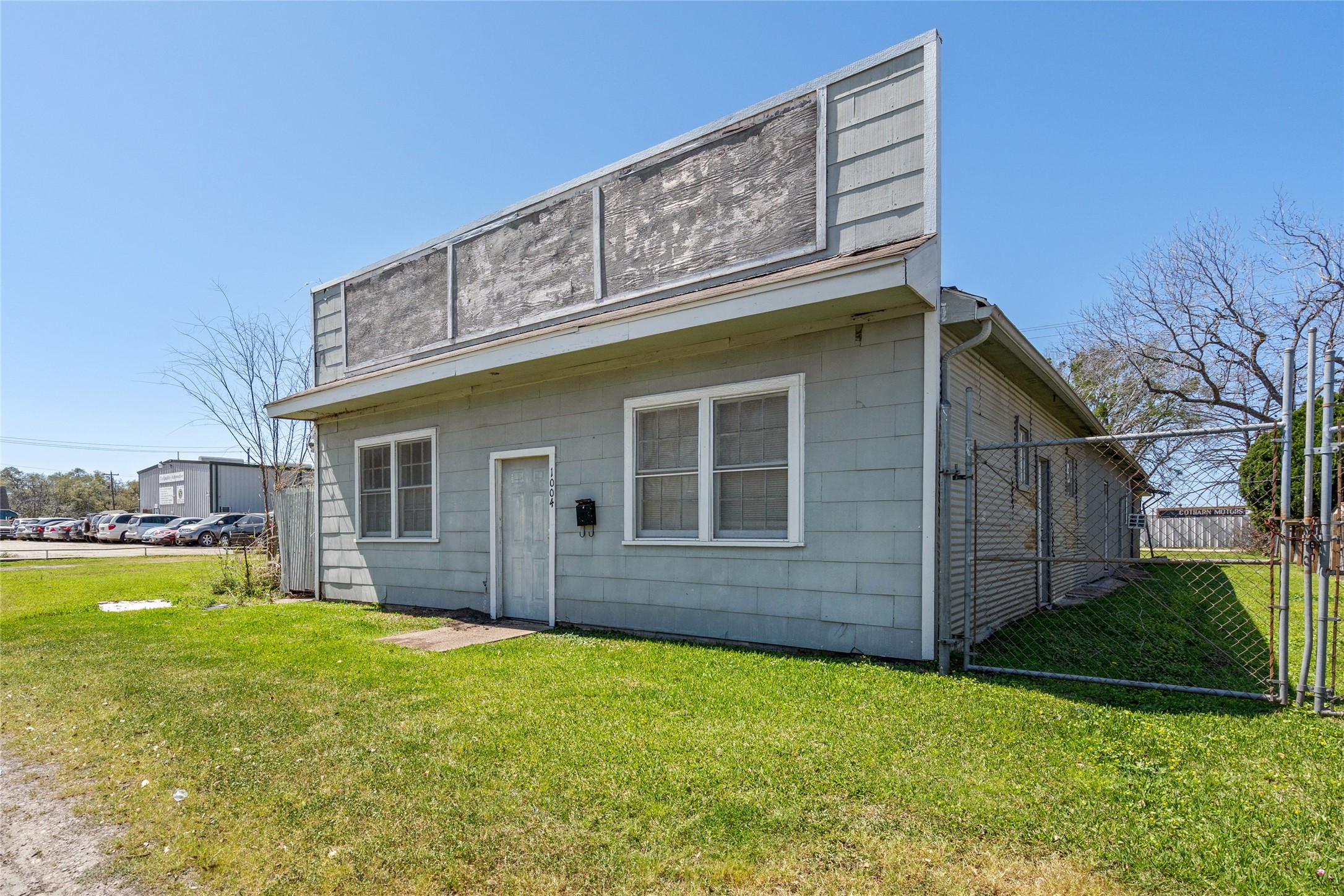 1004 Houston Street Rosenberg, TX 77471 - Photo 4 of 7 Closer view of the existing building on the lot, showcasing the front entrance and side yard area. Perfect for investors looking for a tear-down opportunity with great visibility on a busy street corner.