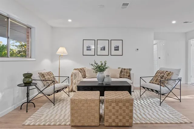 a living room with couches and kitchen view with wooden floor