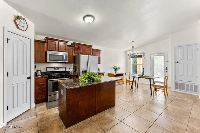 a kitchen with stainless steel appliances kitchen island granite countertop a stove top oven a sink a dining table and chairs