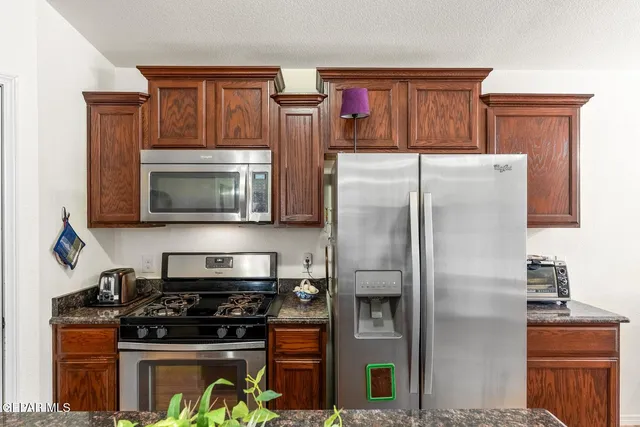 a kitchen with granite countertop a stove microwave and refrigerator