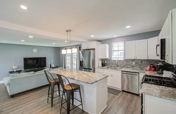 a kitchen with a stove a sink dishwasher a dining table and chairs with wooden floor