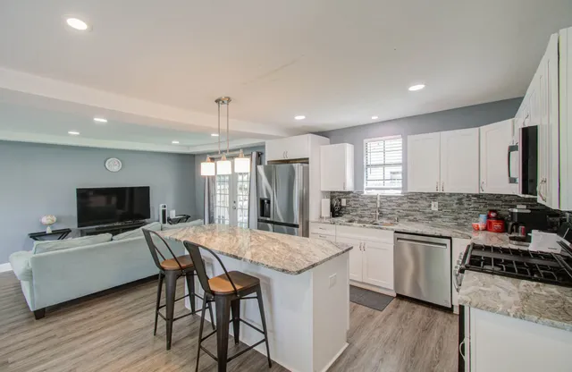 a kitchen with a stove a sink dishwasher a dining table and chairs with wooden floor