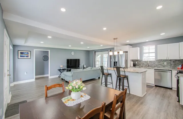 a living room with furniture kitchen view and a wooden floor