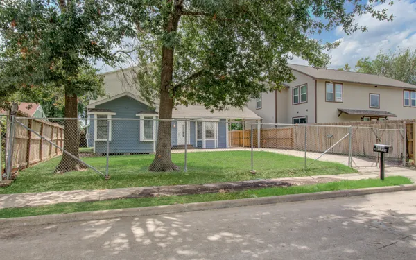 a view of a house with a yard and large tree