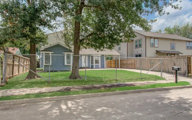 a view of a house with a yard and large tree
