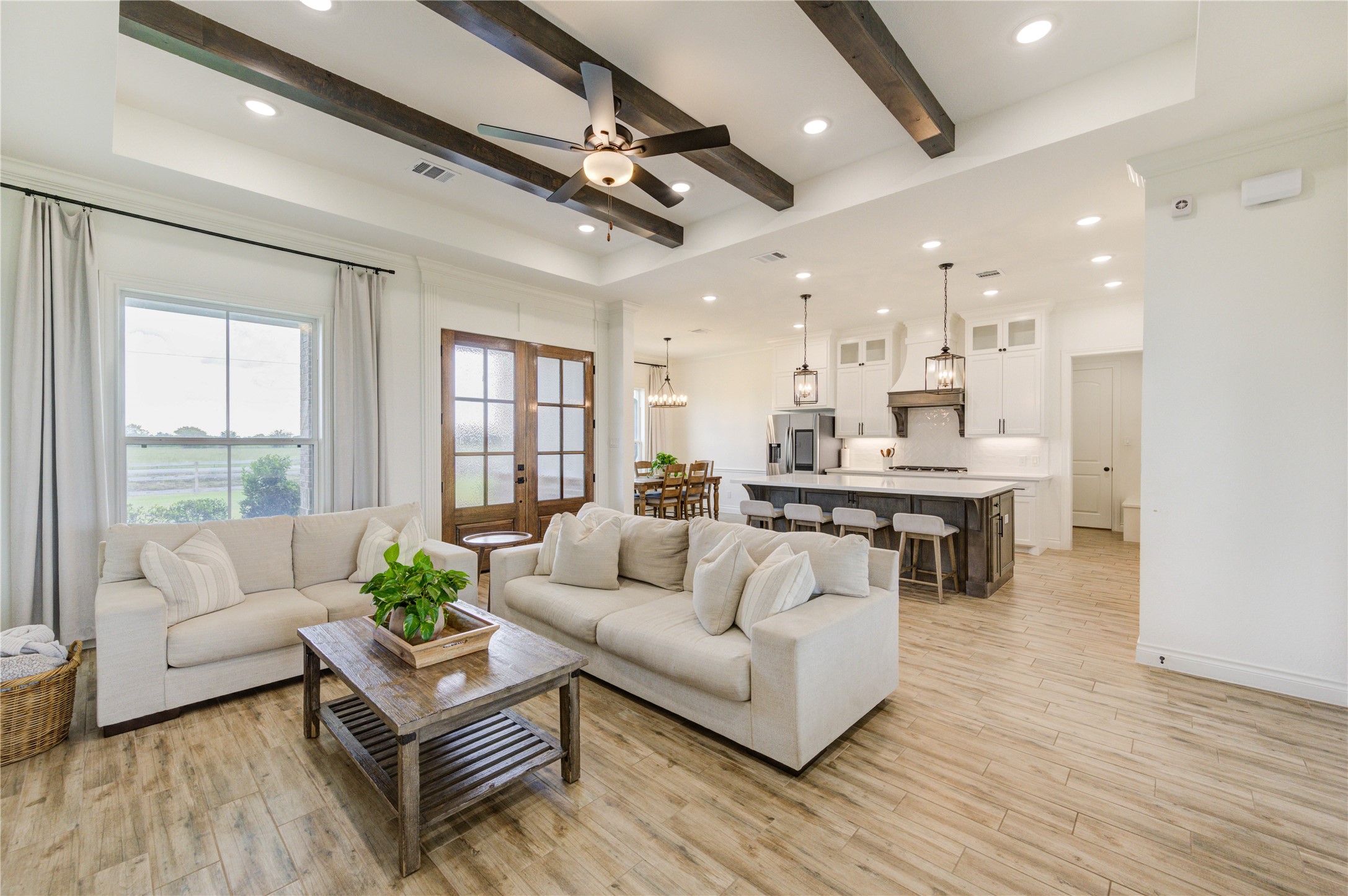 Open-concept living area with beamed ceiling and wood-look tile floors