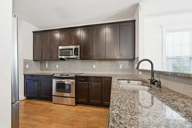 a kitchen with stainless steel appliances granite countertop a refrigerator a stove and a sink