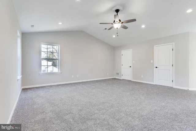 an empty room with chandelier fan and windows