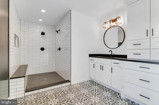 a bathroom with a granite countertop sink a mirror and shower
