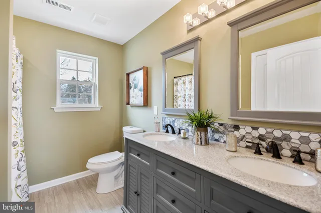 a bathroom with double vanity sinks a toilet and a mirror