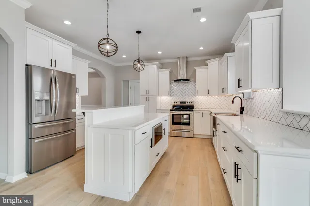 a large kitchen with stainless steel appliances granite countertop a lot of cabinets and refrigerator