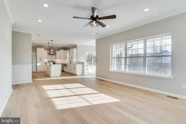 a view of an empty room with a window and a kitchen