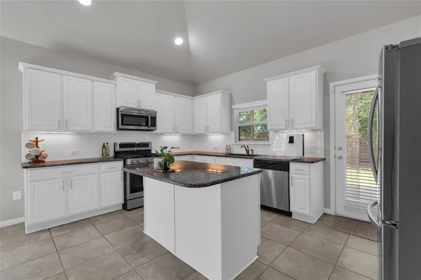 a kitchen with cabinets appliances a sink and a window