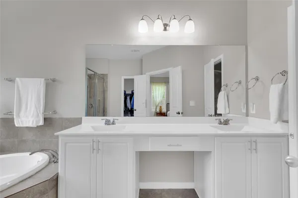 a bathroom with double vanity sinks a vanity a lamp and a mirror