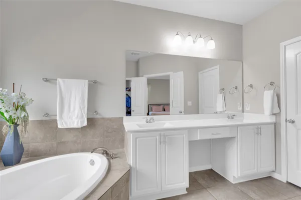 a bathroom with a bathtub a double vanity sink and a large mirror