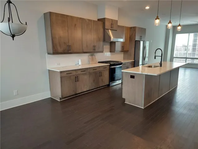 a kitchen with stainless steel appliances a sink a stove a refrigerator cabinets and a counter top space