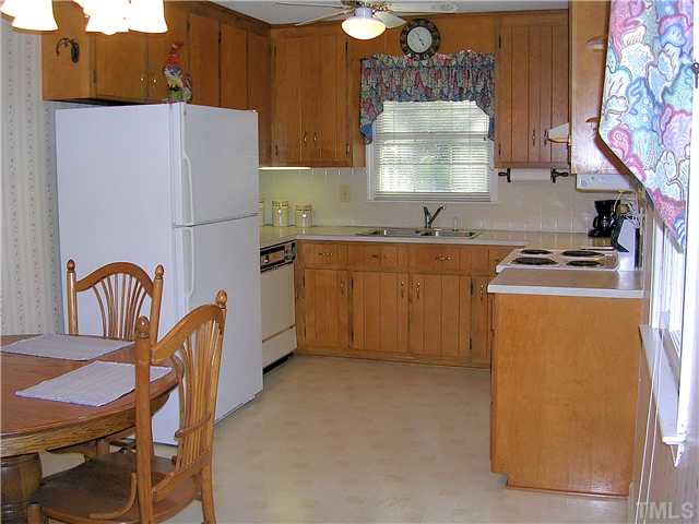 5814 Geoffrey Road Durham, NC 27712 - Photo 9 of 22 a kitchen with granite countertop a stove a sink dishwasher a dining table and chairs with wooden floor