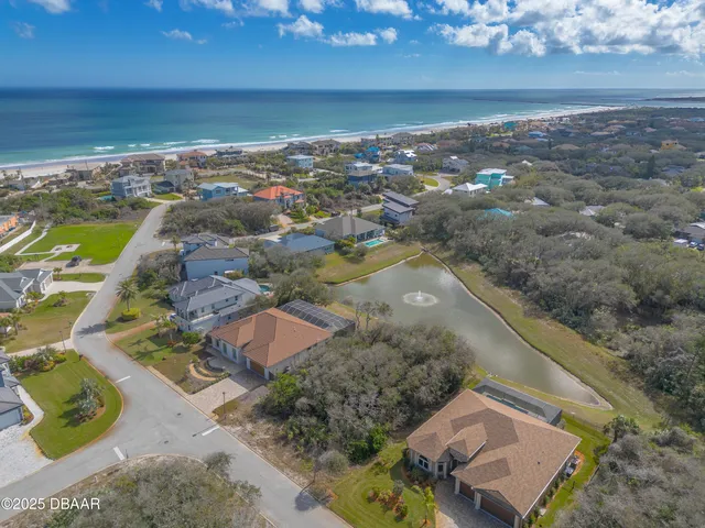 an aerial view of ocean beach and residential houses with outdoor space