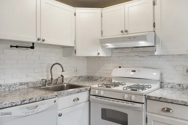a kitchen with granite countertop white cabinets and white appliances