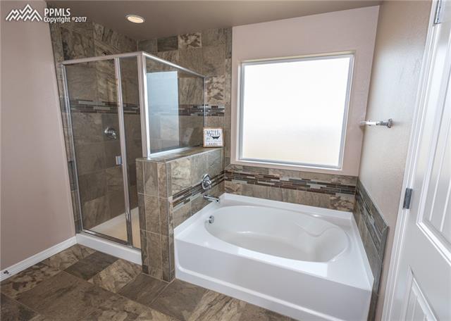 2105 Reed Grass Way Colorado Springs, CO 80915 - Photo 14 of 23 Standing shower and soaking garden tub include designer tile surrounds with a mosaic tile accent.