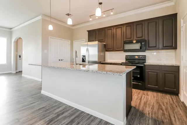a kitchen with kitchen island granite countertop wooden floors white cabinets and stainless steel appliances