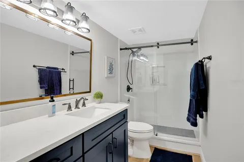 a bathroom with a sink a toilet a mirror and shower