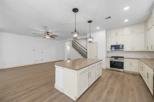 a kitchen with stainless steel appliances white cabinets and wooden floor