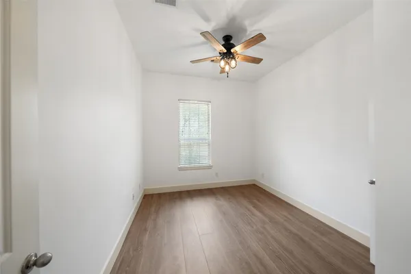 a view of empty room with wooden floor and fan