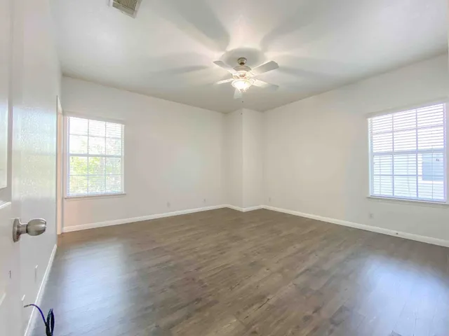 a view of an empty room with a window and wooden floor