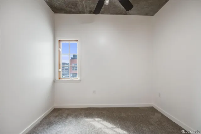 an empty room with a chandelier fan and windows