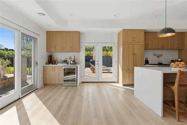 a kitchen with stainless steel appliances a stove a sink a refrigerator white cabinets and wooden floor