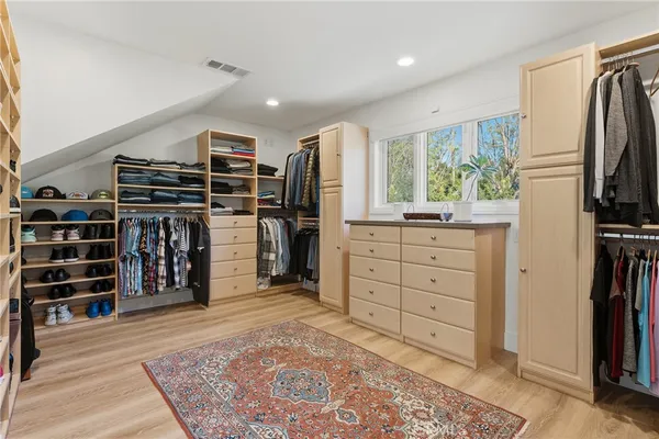 a view of walk in closet with clothes and shoes