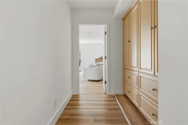 a view of a hallway with wooden floor and a bathroom