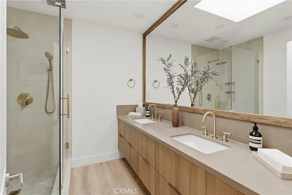 a bathroom with double vanity sink a mirror and a shower