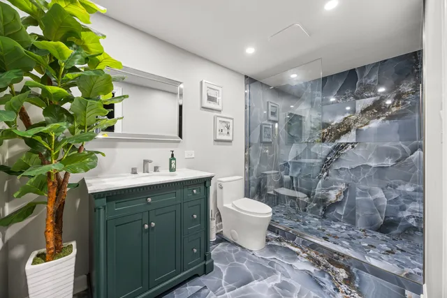 a spacious bathroom with a granite countertop sink a toilet a mirror and shower