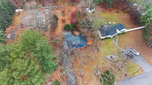 an aerial view of a house with a yard and a large tree