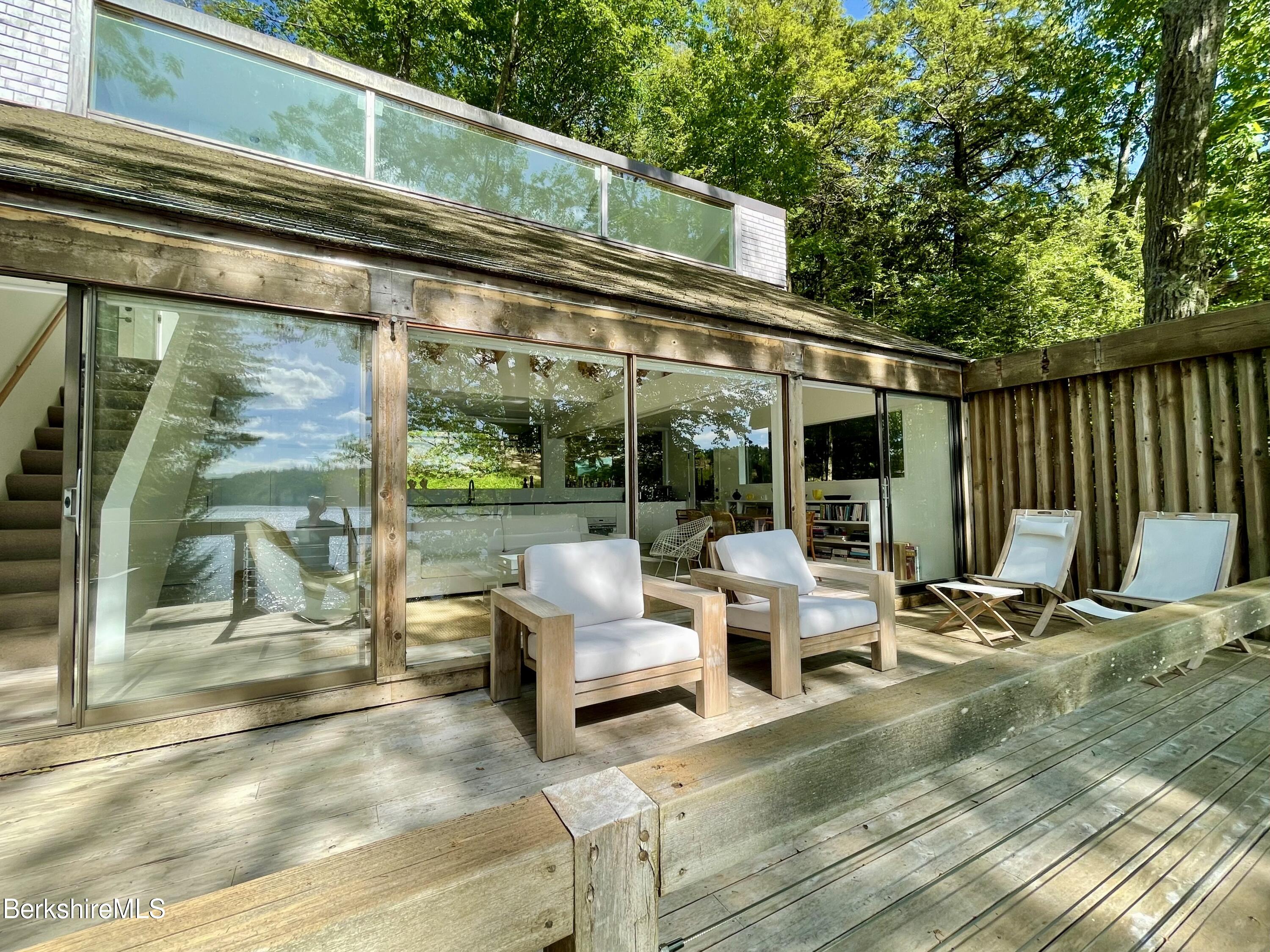 36 Elephant Rock Road Monterey, MA 01245 - Photo 7 of 30 a view of the patio with couches chairs and floor to ceiling window with wooden floor