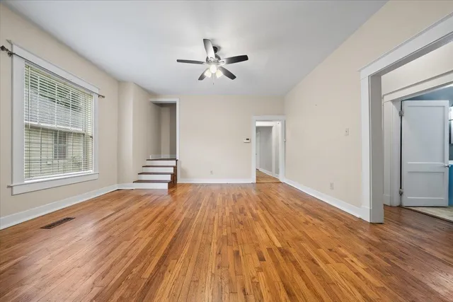 a view of empty room with wooden floor and fan