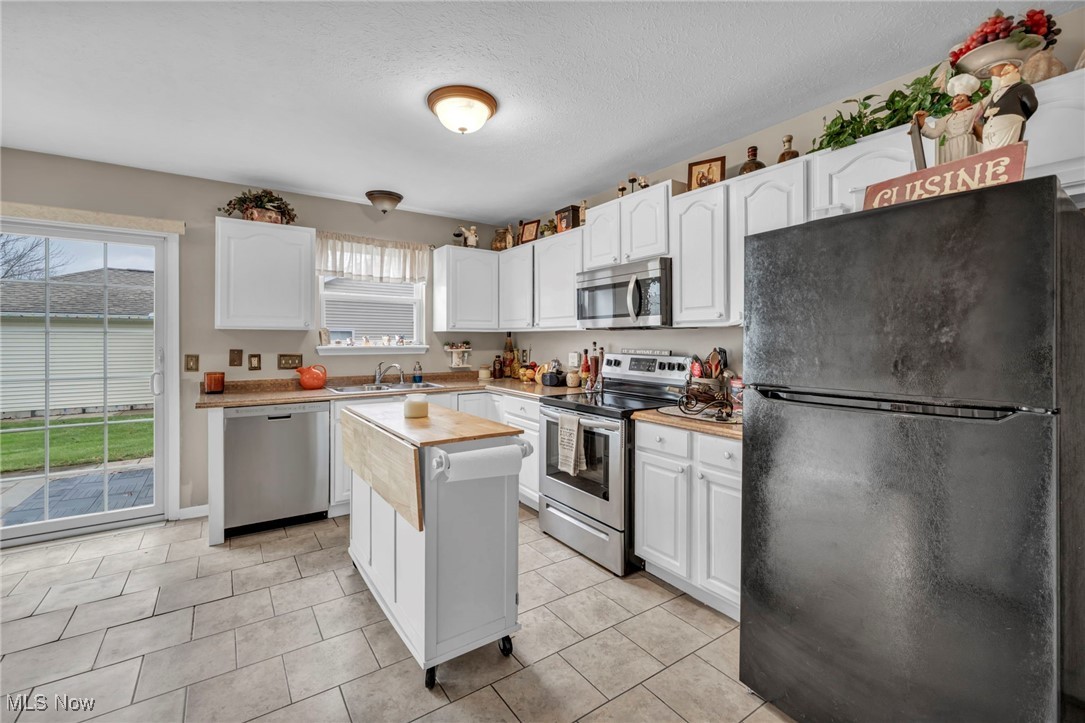 3887 Reeves Lane Medina, OH 44256 - Photo 21 of 42 Kitchen featuring sink, stainless steel appliances, light tile patterned floors, a kitchen island, and white cabinets