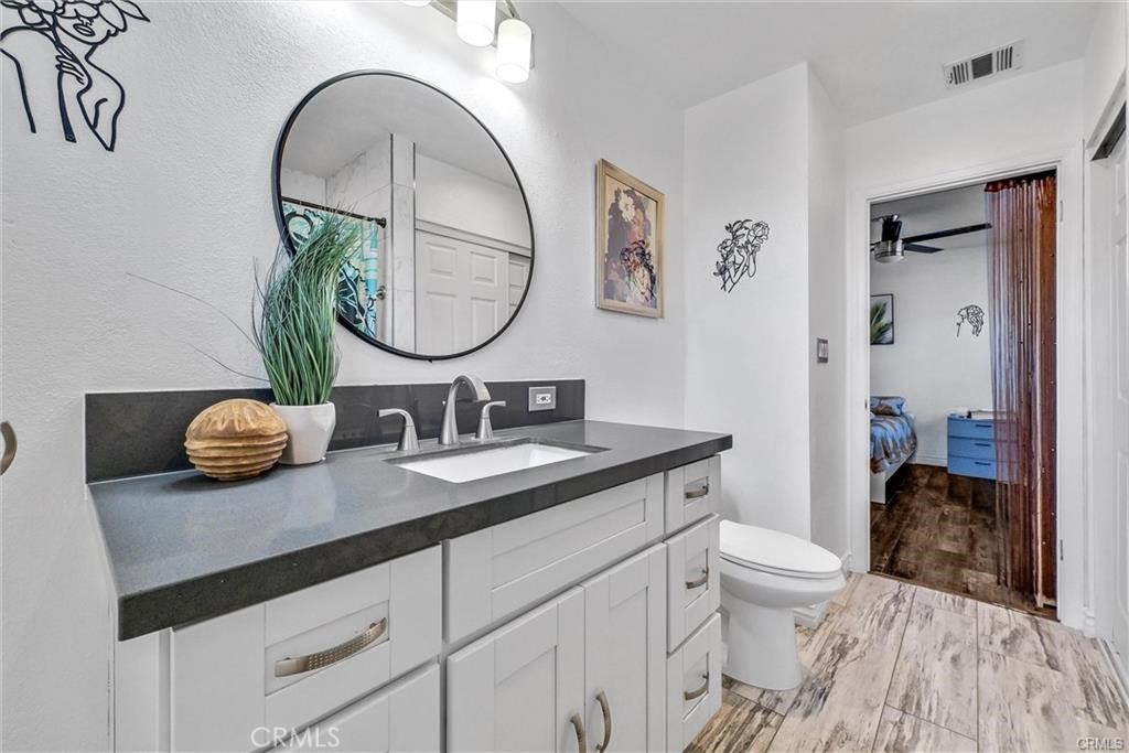 6220 Filkins Avenue Rancho Cucamonga, CA 91737 - Photo 16 of 16 a bathroom with a granite countertop sink a toilet and a mirror