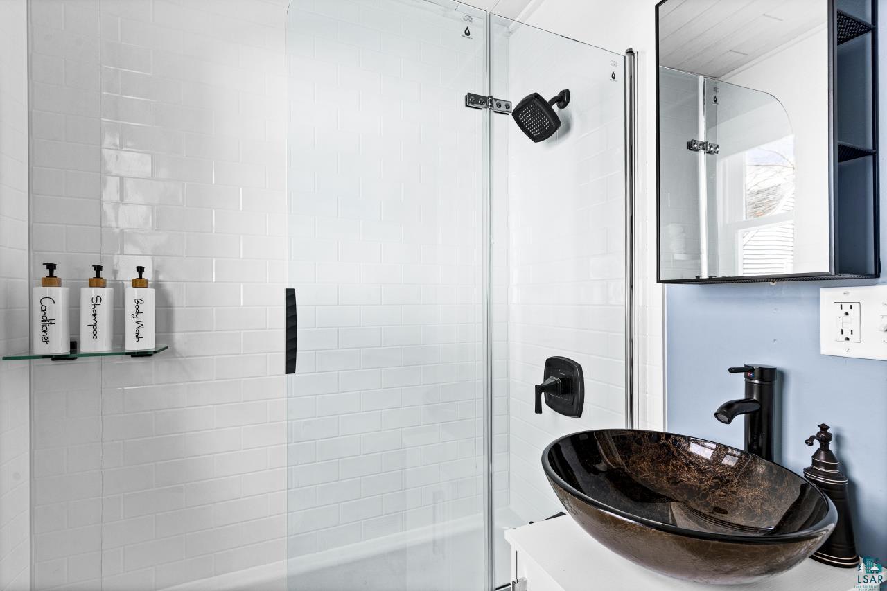 3645 Haines Road Hermantown, MN 55811 - Photo 34 of 35 Contemporary bathroom featuring a glass-enclosed shower with white subway tile, a dark bronze rainfall showerhead, and a matching faucet